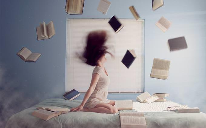 Una mujer sentada en su cama tirando libros
