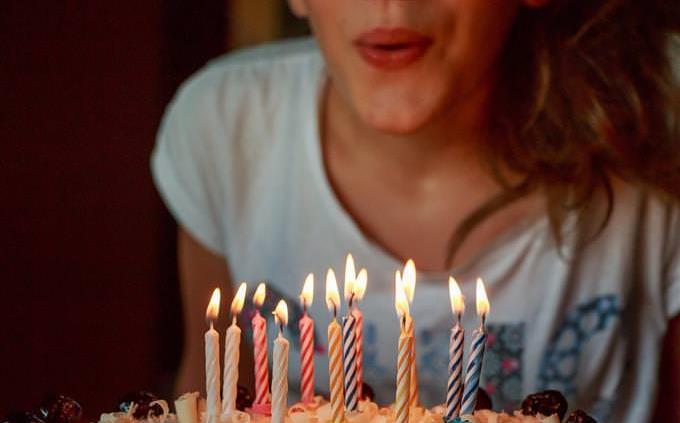 Una mujer soplando velas en un pastel de cumpleaños.
