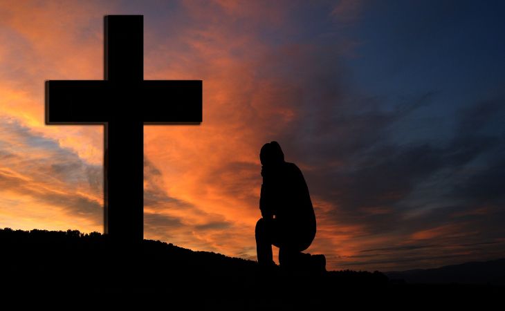 persona rezando frente a una cruz