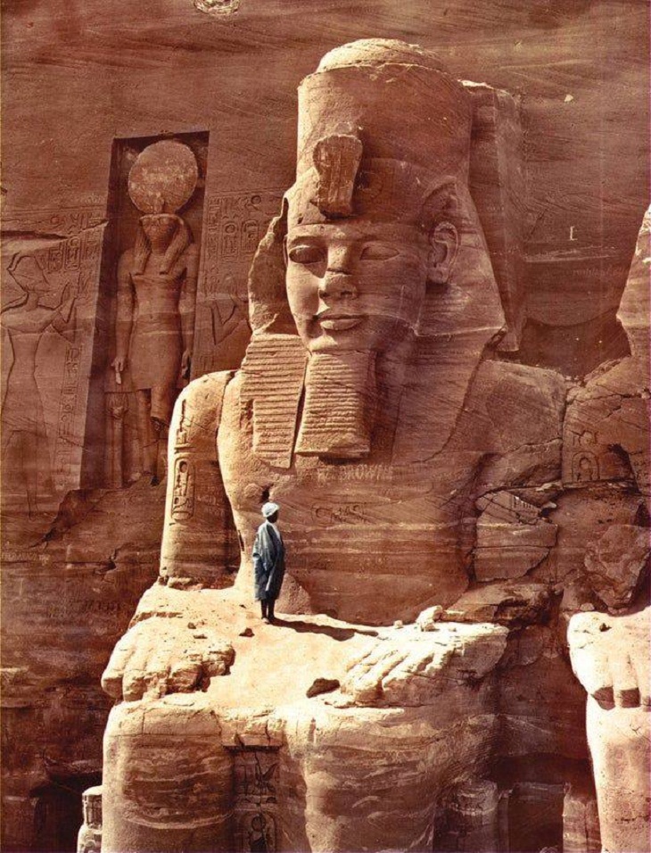 Un hombre se para sobre una enorme figura de Ramsés II en el templo de Abu Simbel en Egipto, 1865