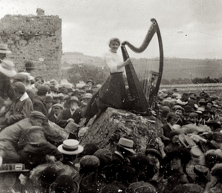 Una joven toca el arpa frente a una gran multitud en la Roca de Cashel en Irlanda, 1910