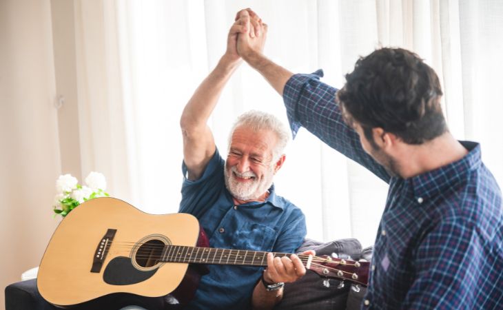 Reflexión: Cuando Nos Convertimos En Padres De Nuestros Padres, adulto mayor y su hijo tocando la guitarra