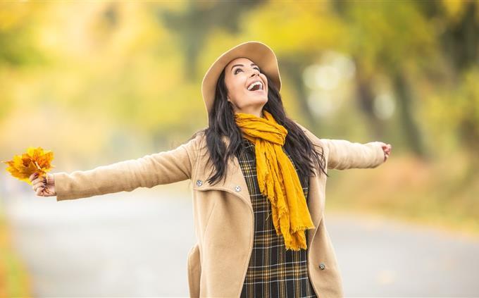 Encuentra las diferencias en otoño: una mujer con ropa otoñal levanta los brazos a los costados