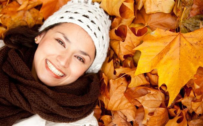 Encuentra las diferencias en otoño: una mujer sonriente acostada sobre hojas caídas