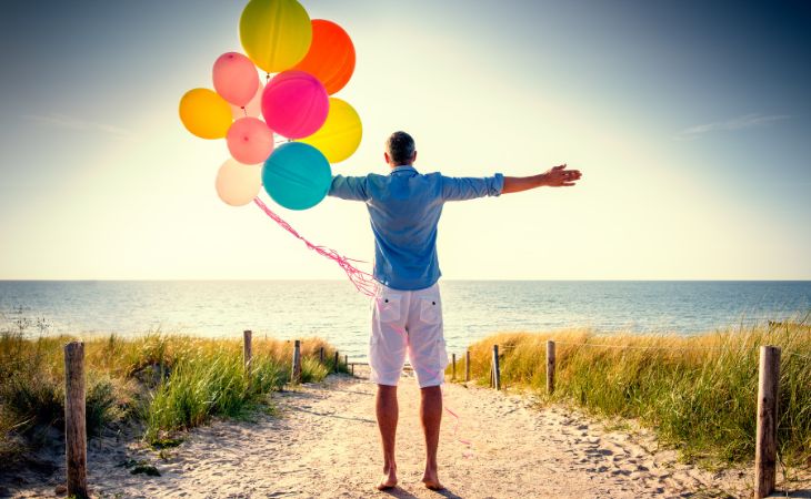 Una Reflexión De Agradecimiento, hombre sostiene globos mirando la playa