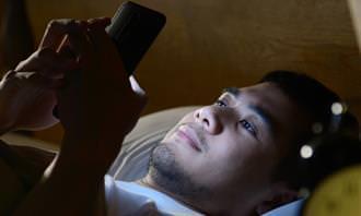 Lo que la rutina matutina revela sobre la personalidad: un hombre en la cama con un teléfono