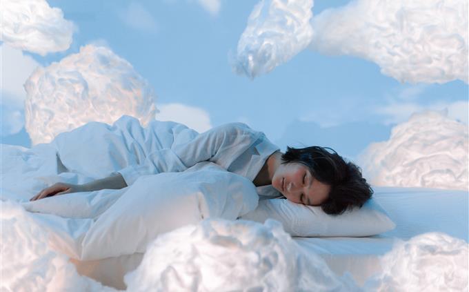 Lo que tus hábitos de sueño revelan sobre tu futuro: Una mujer duerme plácidamente rodeada de nubes