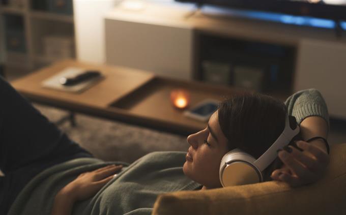 Lo que tus hábitos de sueño revelan sobre tu futuro: una mujer joven duerme en un sofá con auriculares