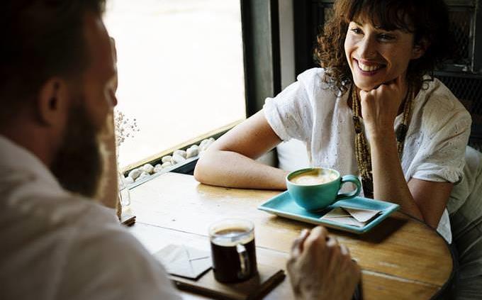 Una mujer conversando con un hombre y sonriendo.