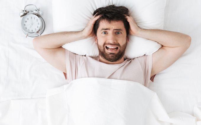 Eres un mentiroso: un hombre estresado junto a un despertador en la cama