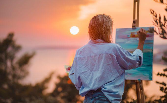 Qué planeta coincide con tu personalidad: Mujer pintando frente a un atardecer
