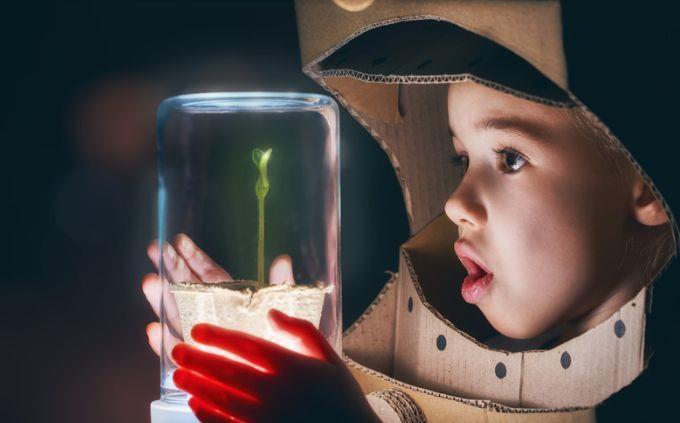 Qué planeta coincide con tu personalidad: un niño disfrazado de astronauta mira una planta sellada en vidrio