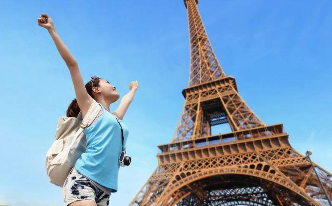 Curiosidades de extrañas costumbres de todo el mundo: Una mujer feliz cerca de la Torre Eiffel