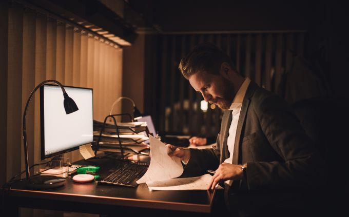 Estás agotado o estresado: un hombre trabaja en la oscuridad frente a una computadora