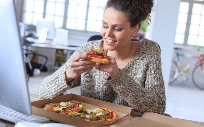 Estás agotado o estresado: mujer comiendo pizza en la oficina
