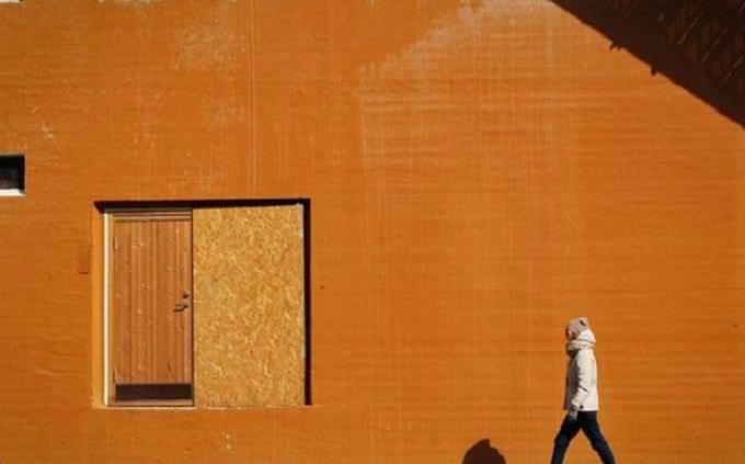 Hombre caminando cerca de la pared naranja