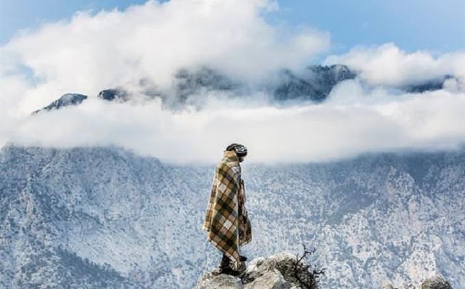 Hombre en manta parado frente a una montaña nevada