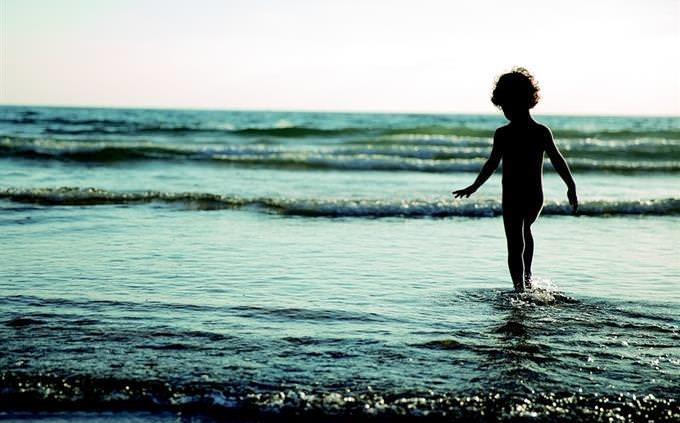 niño en la playa parado en el agua