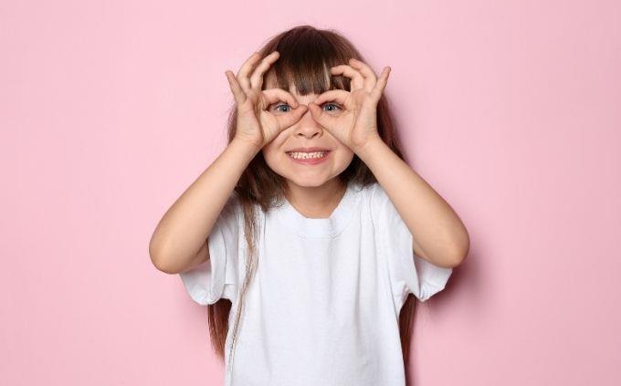 Prueba de visión de números de color: una niña hace gafas con los dedos