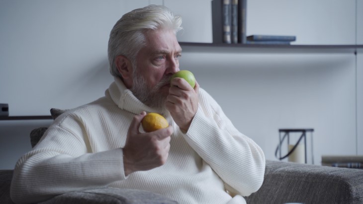 Adulto mayor oliendo una manzana