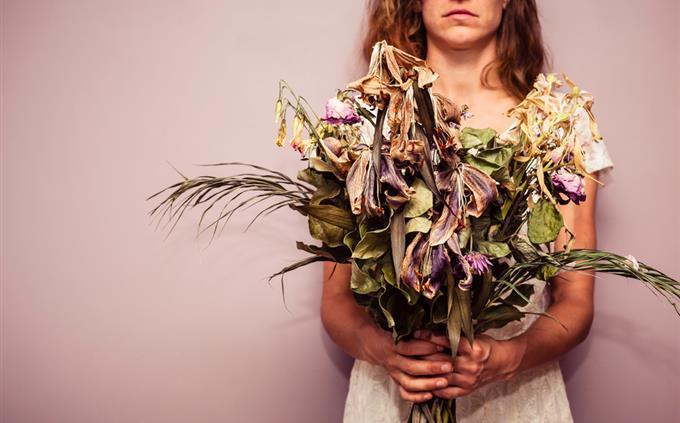 Una prueba de flores y romance: una mujer sostiene un ramo marchito