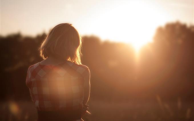 Una prueba de flores y romance: una mujer frente a un atardecer