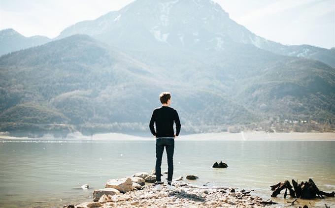Un hombre parado frente a un lago.