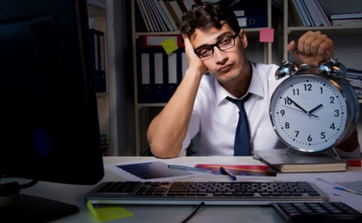 Study on working hours and risk of death: a person sitting in front of a computer holding a clock