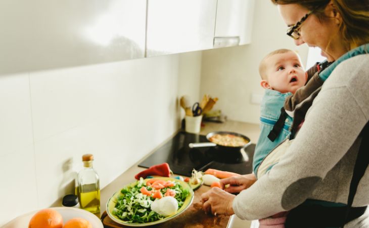 Crianza Koala: Madre cortando una ensalada con bebé en un portabebés